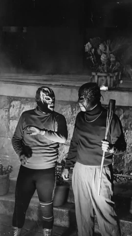 Dos luchadores enmascarados en blanco y negro, entre humo
